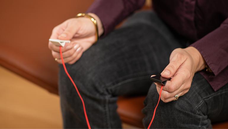Hands holding EMDR bilateral stimulation tappers during a therapy session